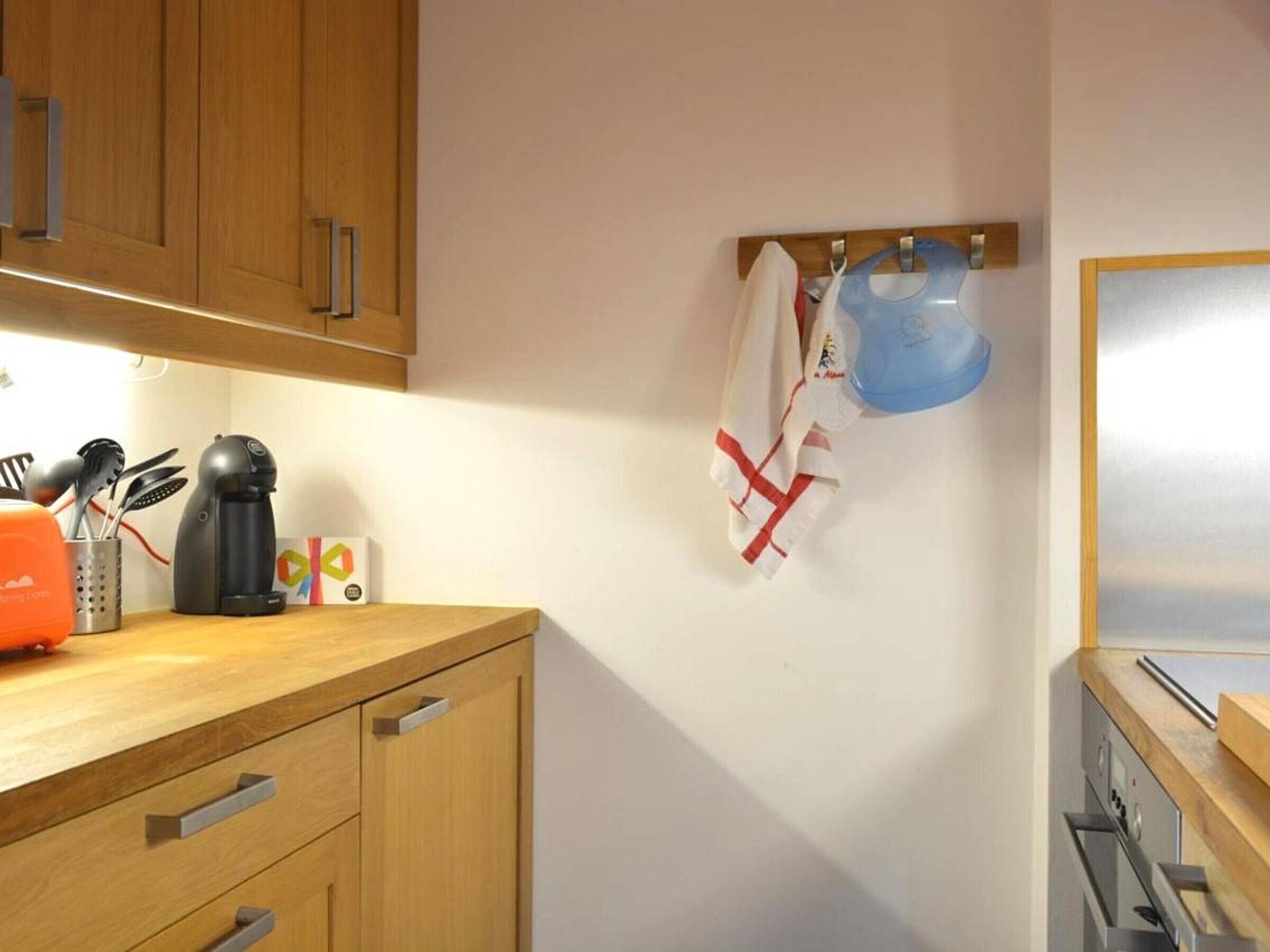 A kitchen with wooden cabinets, a coffee maker, and a kettle on the counter.