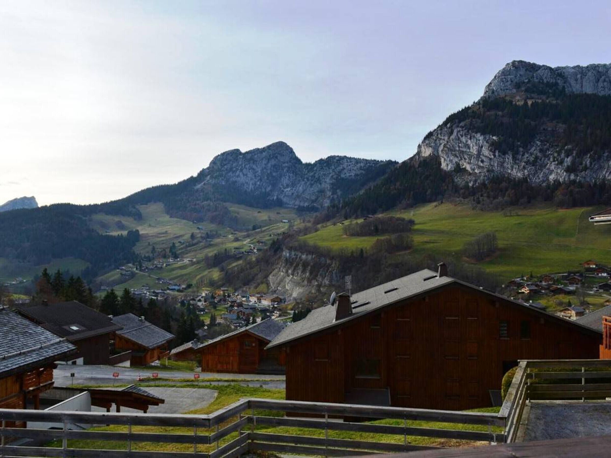 A mountain village with wooden buildings, a paved road, and a view of the surrounding mountains.