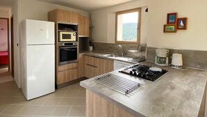 Une cuisine moderne dotée d’un îlot central, d’un four encastré, d’un four à micro-ondes et d’un réfrigérateur.