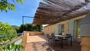 Une terrasse avec une table et des chaises, une pergola et une vue sur le paysage environnant.