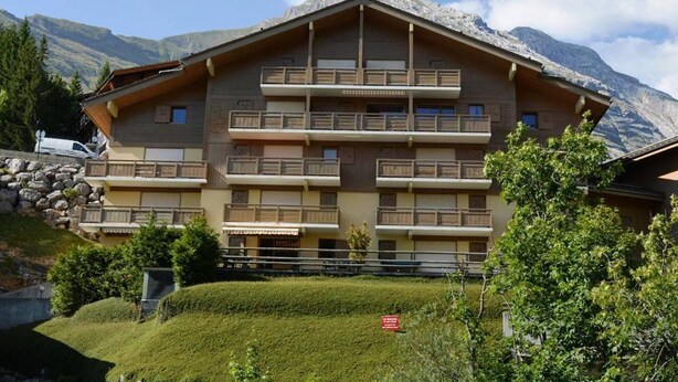 A multi-story hotel with balconies, set against a mountainous backdrop. - 3-room apt, sleeps 6, near shops and slopes, parking included, pets allowed (Le Grand-Bornand)