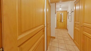 A hallway with wooden doors, a tiled floor, and a ceiling light fixture. - 3-room apt, sleeps 6, near shops and slopes, parking included, pets allowed (Le Grand-Bornand)