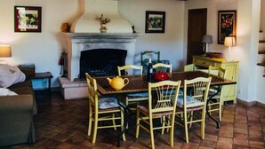 A cozy living room with a fireplace, wooden ceiling beams, and a dining area with chairs and a table. - Vigne Féré BELGENTIER - BELGENTIER (BELGENTIER)