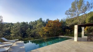A swimming pool with lounge chairs and a pergola, surrounded by trees and hills. - Vigne Féré BELGENTIER - BELGENTIER (BELGENTIER)