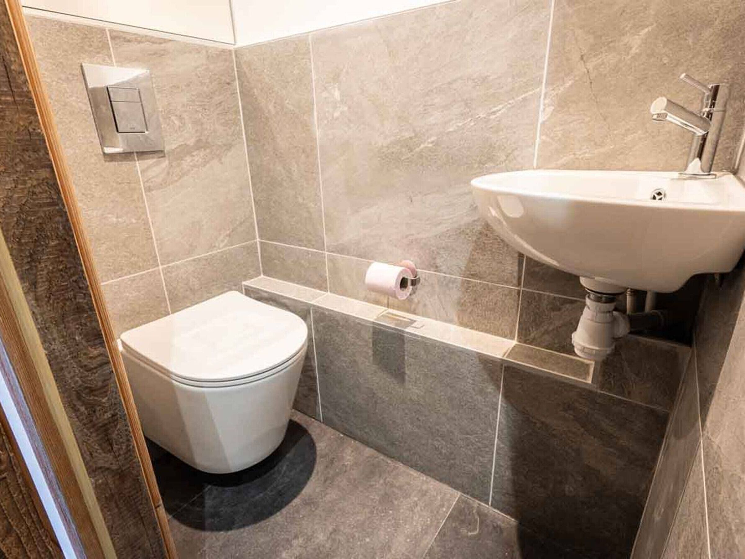 A bathroom with a toilet, a sink, and a toilet paper holder on the wall.