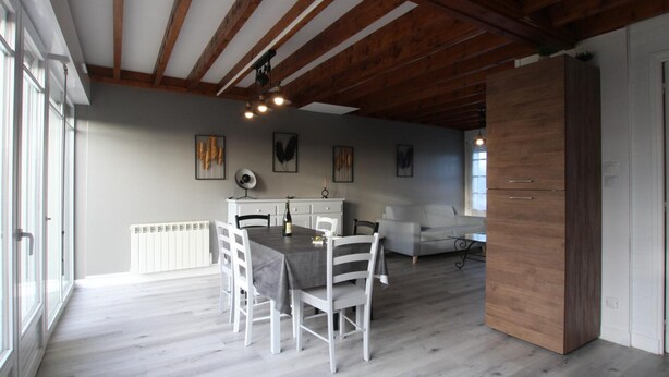 A spacious dining area with a wooden ceiling, white chairs, and a table set for four. - Cozy Cottage in Regional Park, Near D-Day Beach, Sleeps 4. (Liesville-sur-Douve)