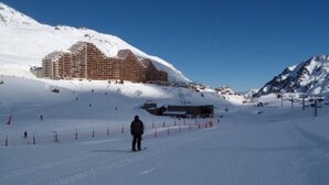 A snow-covered ski slope with a large building in the background, ski lifts, and a person skiing. - Studio 4 ppl, south balcony, dishwasher, pets allowed (La Mongie)