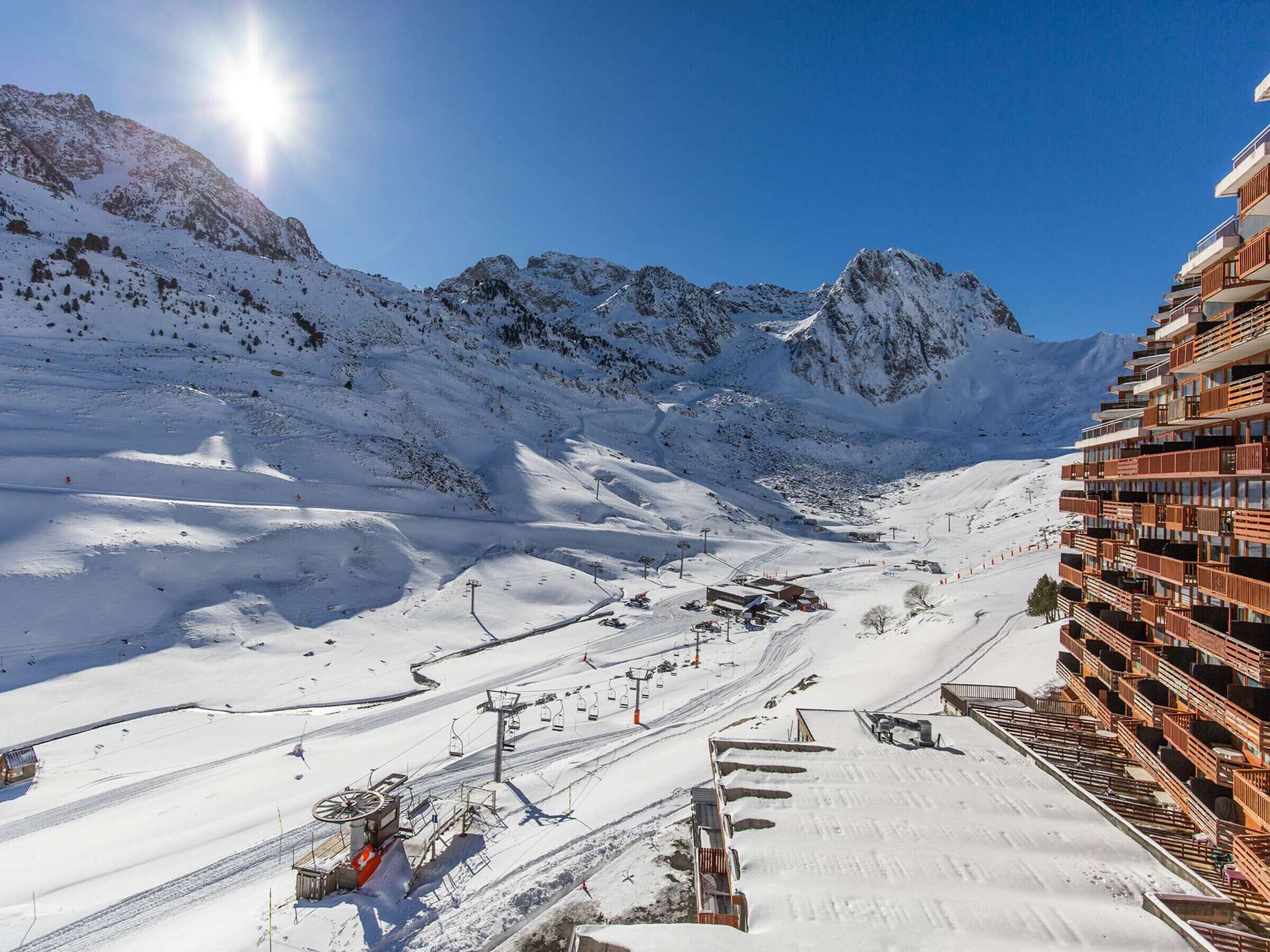 Un paisaje montañoso cubierto de nieve con un telesilla y un edificio moderno con balcones.