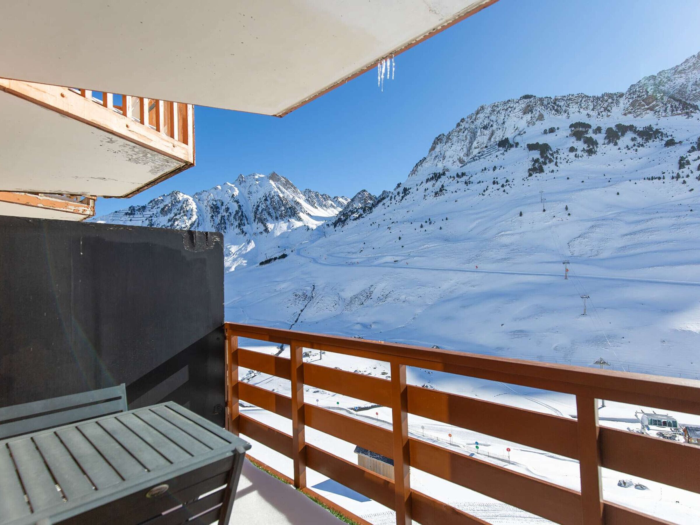 Un balcon offrant une vue sur un paysage montagneux enneigé, avec notamment un télésiège.