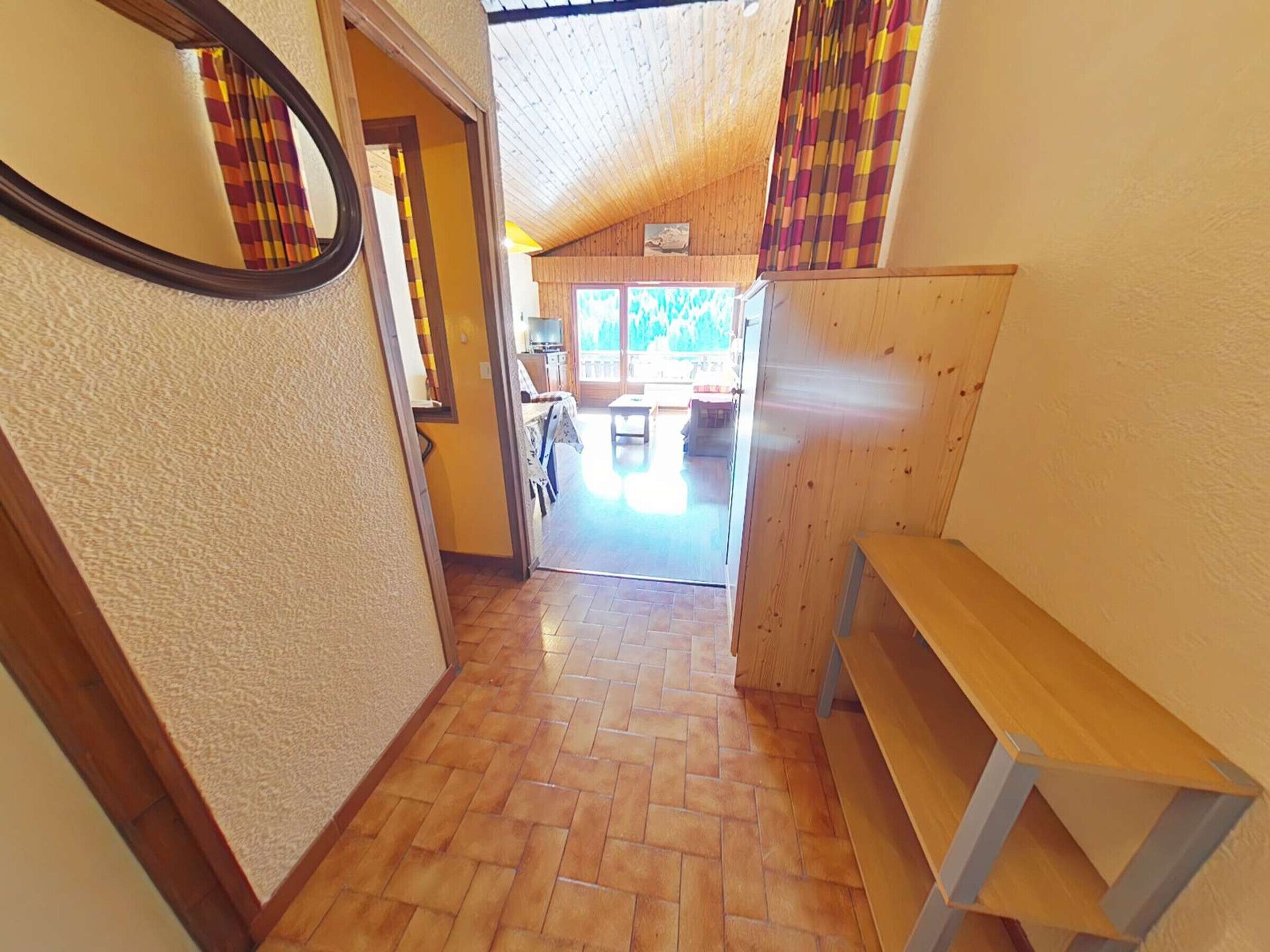 A hallway leading to a dining area with a wooden floor and a bench.
