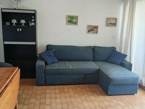 Un soggiorno con un divano blu scuro, un tavolino in legno e un mobile contenitore nero con ripiani.