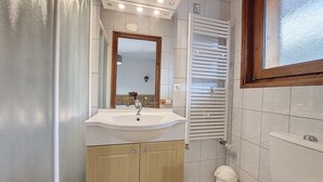 A bathroom with a sink, mirror, towel rack, and toilet.
