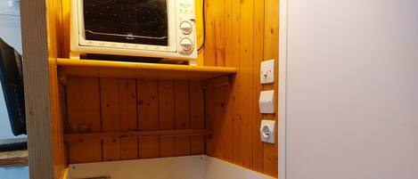 Una cocina compacta con microondas integrado, un lavamanos y una estufa.