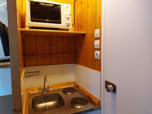 Compact kitchenette with microwave oven, stainless steel sink, and ample storage.