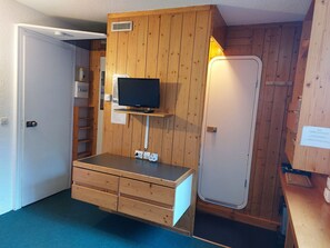 Cozy retreat with a flat-screen TV, cabinet, and a small window.