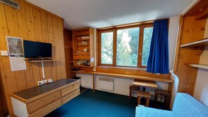 Ett kompakt kök med träskåp, en inbyggd TV och ett fönster med en blå gardin.