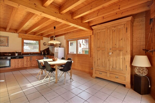 A wooden cabin interior with a kitchen, dining area, and large wardrobe.