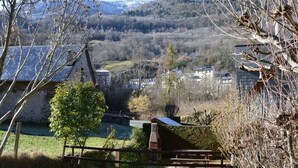 A rural landscape with a stone building, a tree, and a bench.