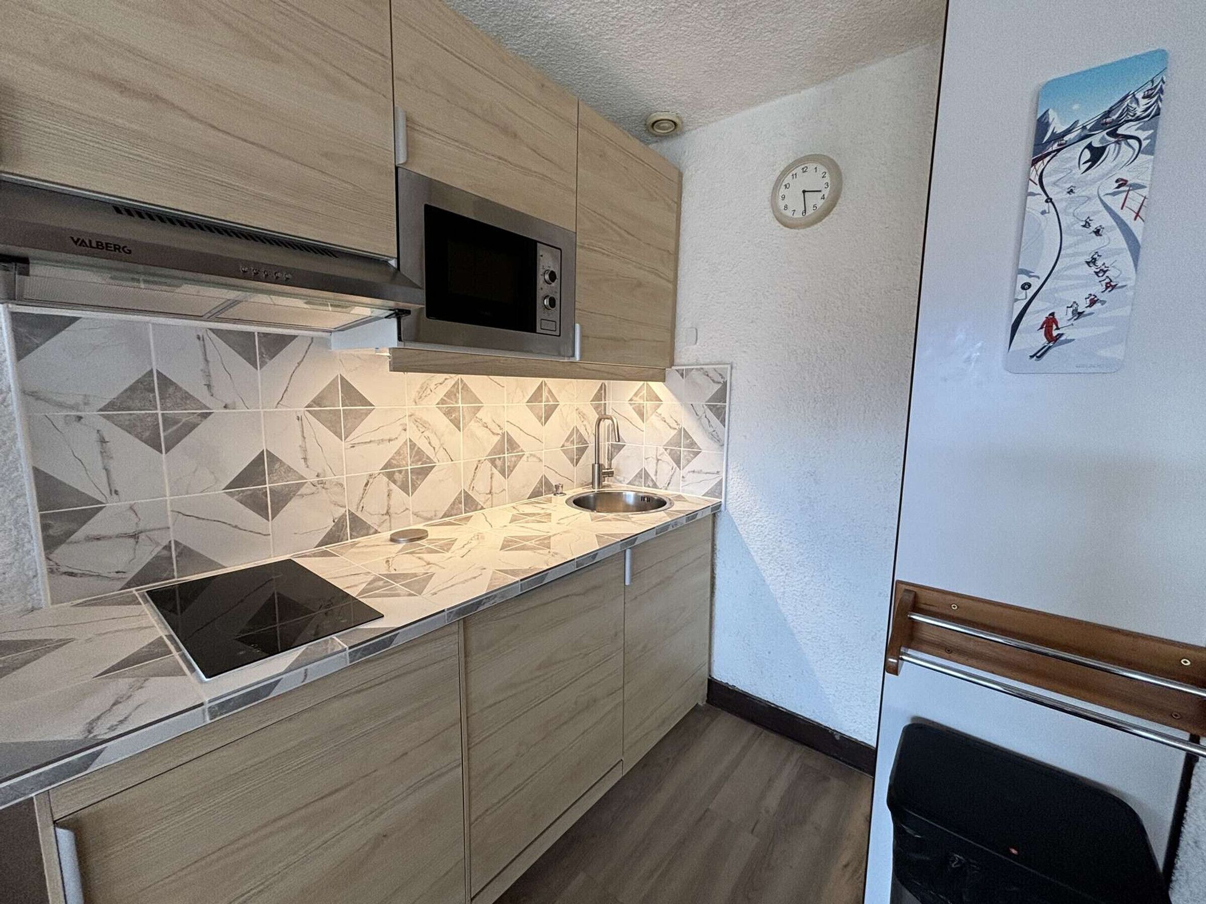 A compact kitchen with a microwave, sink, and wooden cabinets.