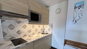 A compact kitchen with a microwave, sink, and wooden cabinets.