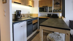 A compact kitchen with a refrigerator, coffee maker, microwave, and a small sink.
