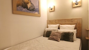 A bedroom with a wooden headboard, white bedding, and a painting of polar bears on the wall.