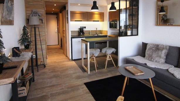 A compact living space with a kitchenette, a sofa, a coffee table, and a small dining area.
