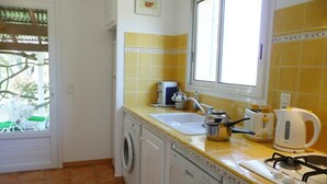 A compact kitchen with a washing machine, a sink, a stove, and a window.