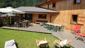 Une cabane en bois dotée d’une terrasse, de meubles de jardin et offrant une vue sur les montagnes.