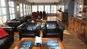 Un salón amplio con sofás de cuero, una mesa de centro con revistas y un gran ventanal que proporciona luz natural.