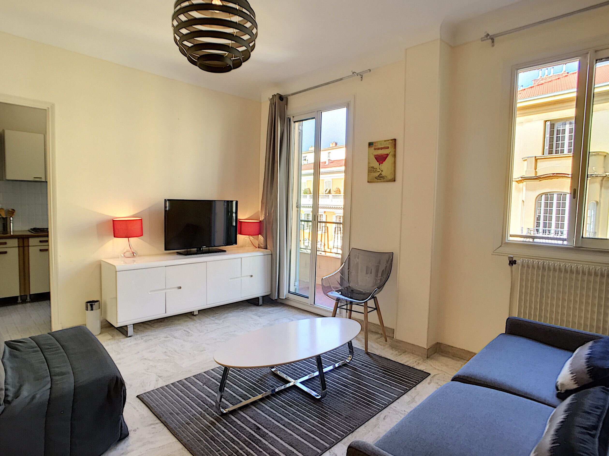 Un salon moderne avec un téléviseur à écran plat, une table à manger, un canapé et un fauteuil.