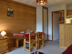 Un comedor de madera con una mesa dispuesta para dos, un banco de madera, una lámpara y un cuadro en la pared.