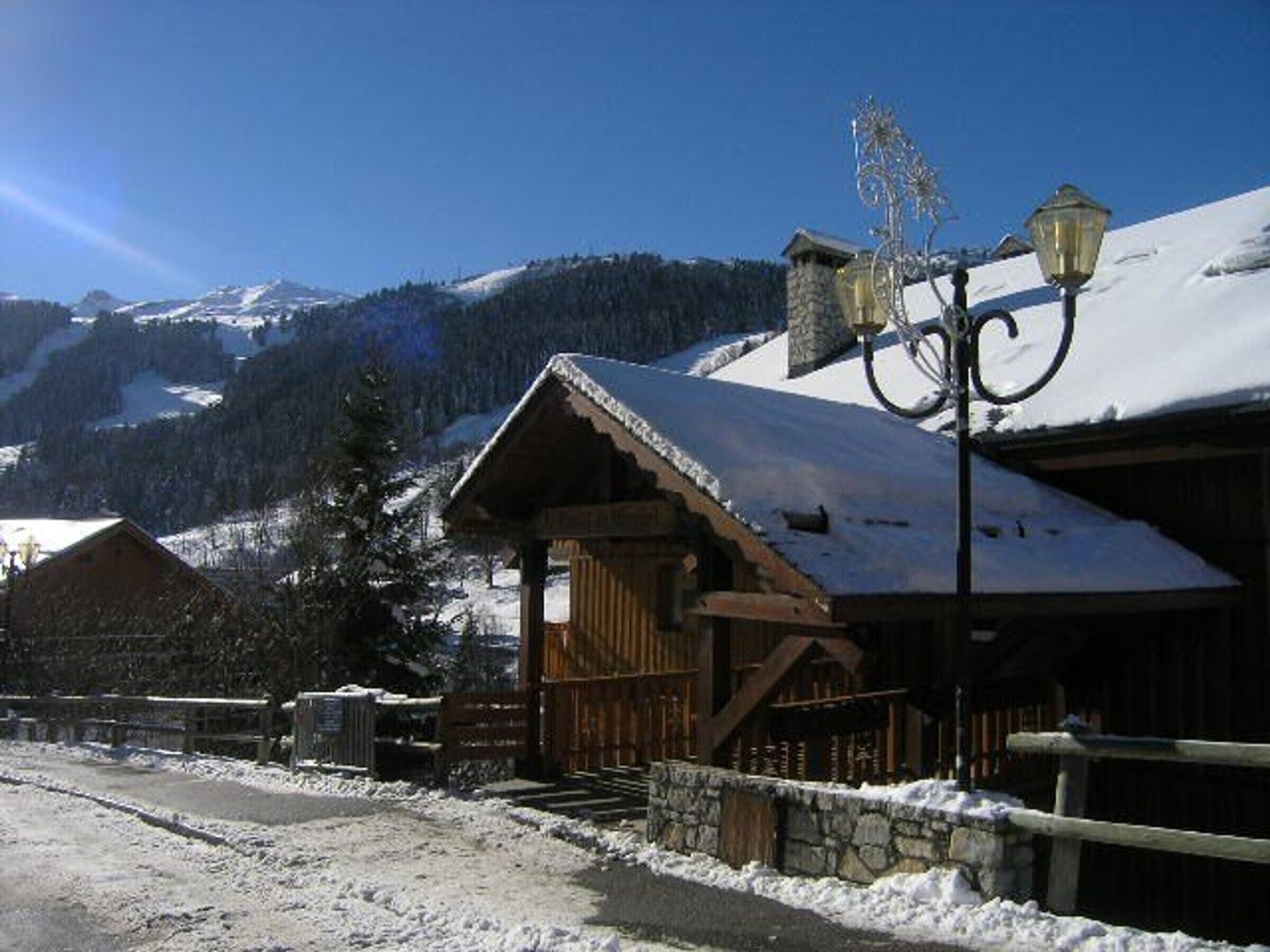 Una cabaña de madera con techo nevado, pared de piedra y farola.