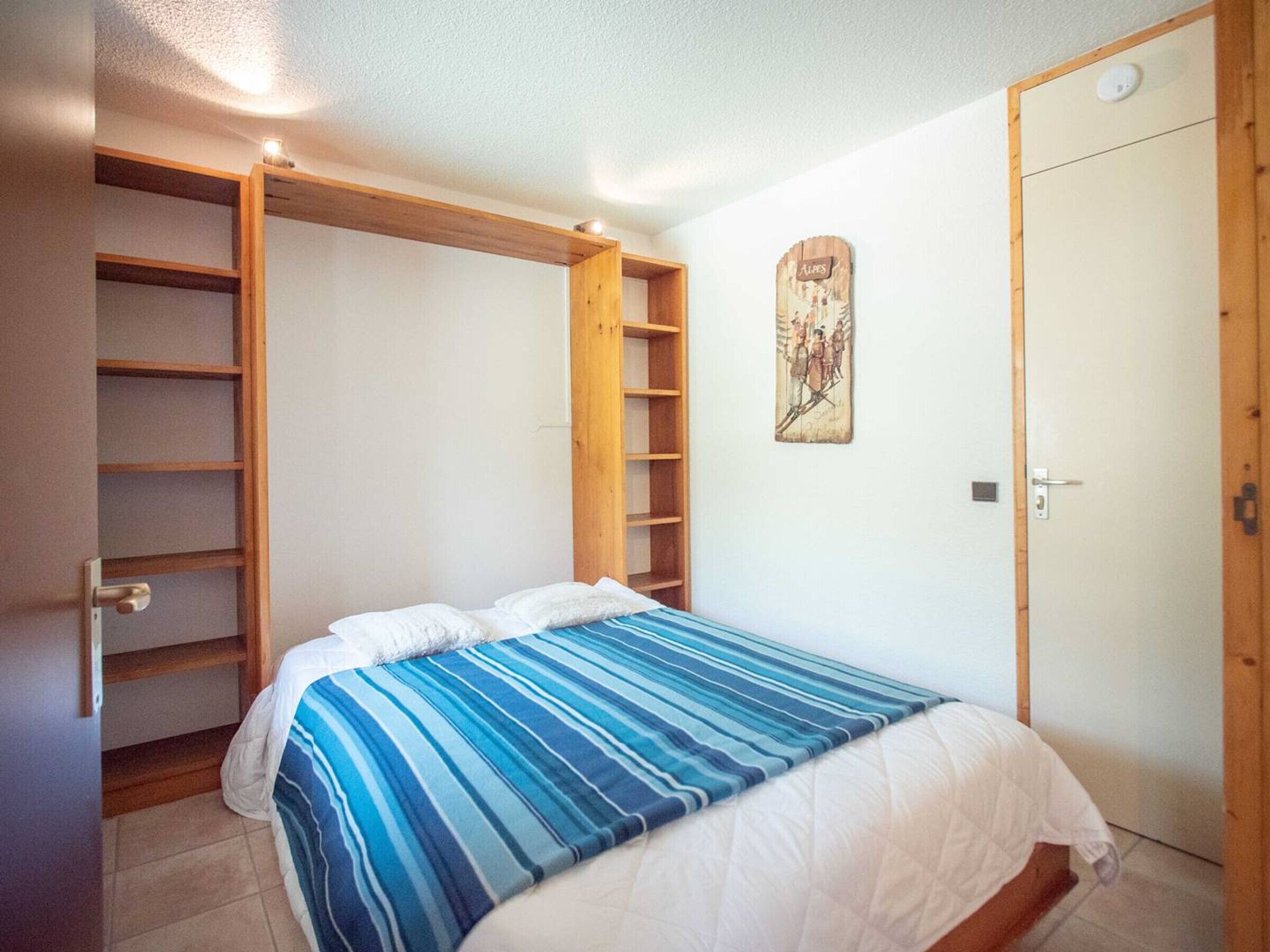 A bedroom with a bed, a wardrobe, and a shelf unit.