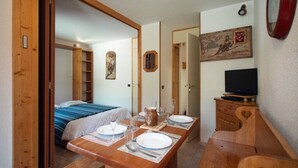 Una camera compatta con un letto, un tavolo da pranzo per due persone, una televisione e uno specchio a parete.
