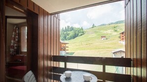 Un balcone con tavolo e sedie, affaccia su un paesaggio verde con edifici.