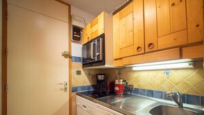 Una cucina compatta con mobili in legno, un forno a microonde, una macchina da caffè e una lavastoviglie.