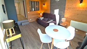 Ein modernes Wohnzimmer mit einer Couch, einem Esstisch mit Stühlen und einer Treppe, die in eine andere Ebene führt.