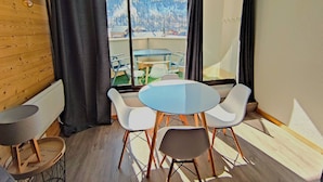 Ein modernes Zimmer mit einem runden Tisch und vier Stühlen, großen Fenstern mit Blick auf eine verschneite Landschaft und einer Holzverkleidung.