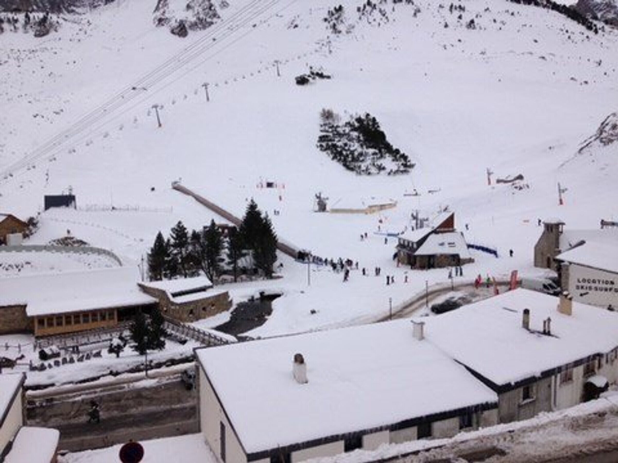 En snötäckt by med byggnader, en skidlift och en skylt som visar platsen.