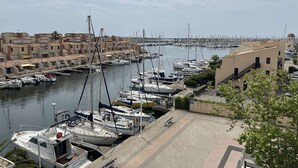 A marina with boats docked, a waterfront promenade, and buildings with balconies. - Renovated 2-bedroom apartment with pool and parking, sleeps 6 near the beach (Gruissan)