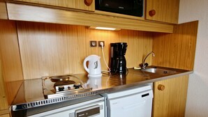 Una kitchenette compacta con microondas, cafetera y un refrigerador pequeño.