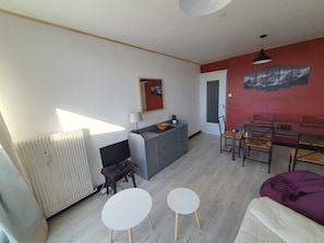 A living room with a dining area, a TV, and a radiator.