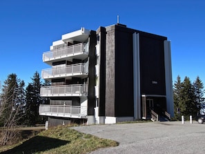 A multi-story building with balconies, a garage entrance, and a clear sky.