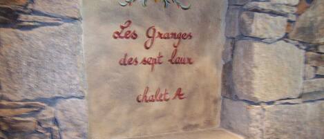A stone wall with a carved plaque reading "Les Granges des sept laur chalet A".
