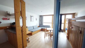 En hyggelig, åben stue med en træbænk, en sofa og et spisebord.