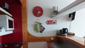 Et køkken med rød væg, et ur, en kaffemaskine og et skilt, der angiver en restaurant med ski.