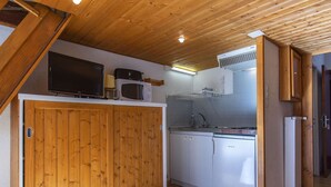 A compact kitchen with wooden cabinets, a microwave, a stove, and a refrigerator.