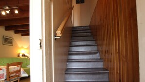 Una scala con ringhiere in legno e un divano verde sullo sfondo.