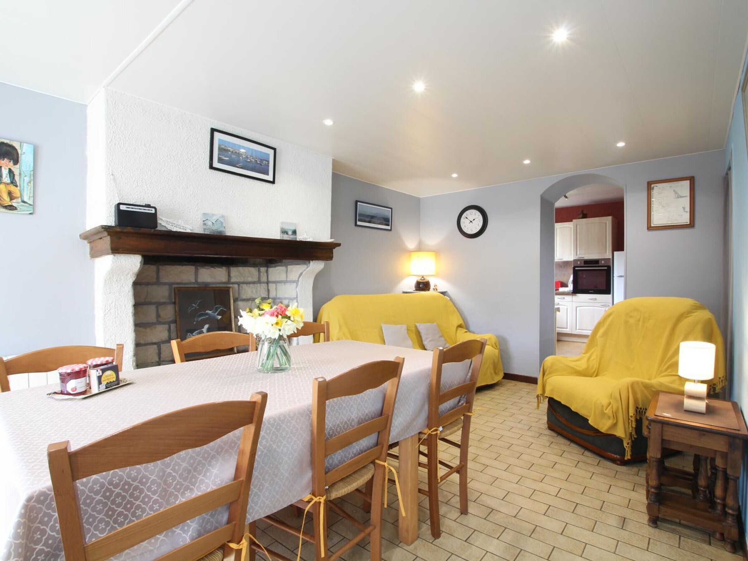 A dining area with a table set for four, a fireplace, and a yellow armchair.